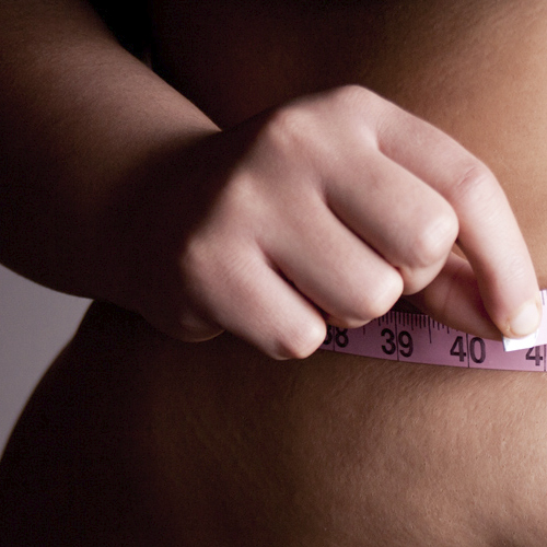 Obese woman measuring herself with tape