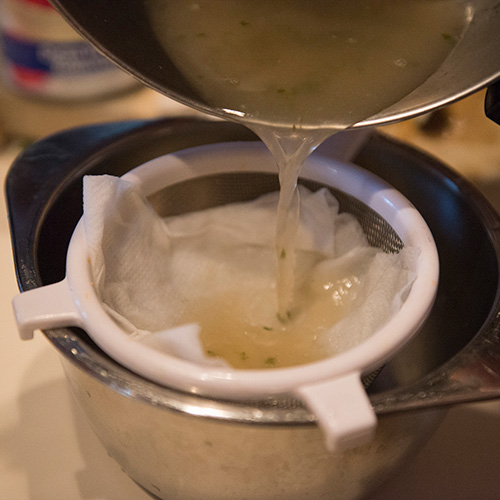 Broth being strained in a colander